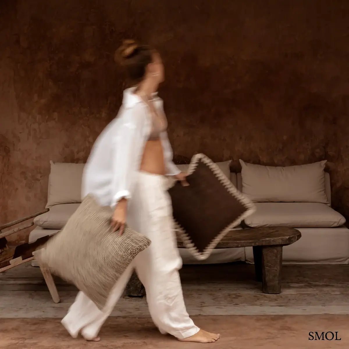 Barna pamut díszpárnahuzat fehér kézi horgolású szegéllyel, 50x50 cm-es méretben, nő kezében