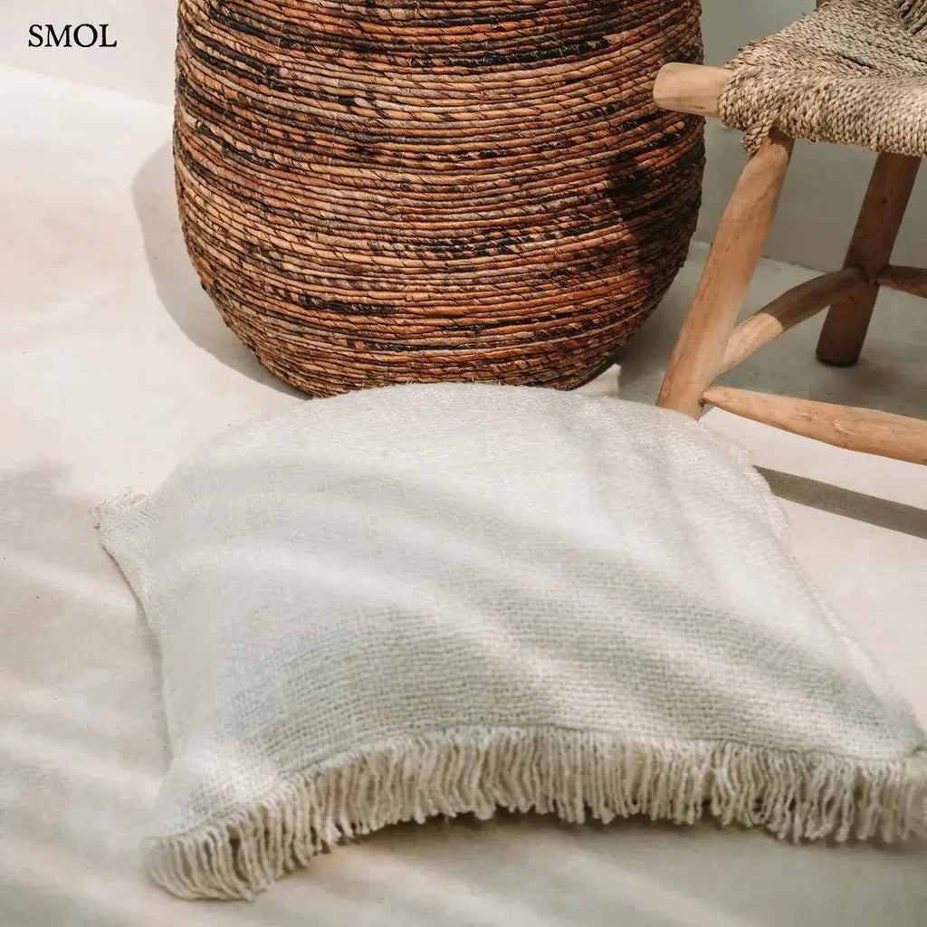 Krémszínű, kézzel szőtt pamut díszpárnahuzat rojtos szélekkel és rusztikus textúrával, padlón