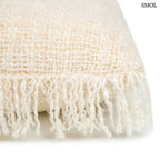 Krémszínű, kézzel szőtt pamut díszpárnahuzat rojtos szélekkel és rusztikus textúrával, sarok nagyítva