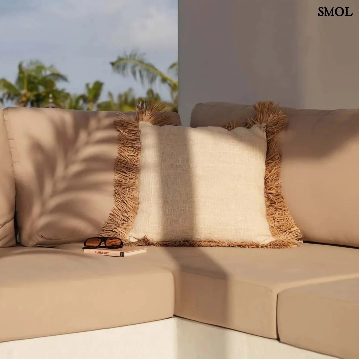 Fehér pamut és raffia díszpárnahuzat rojtokkal teraszon, napszemüveggel