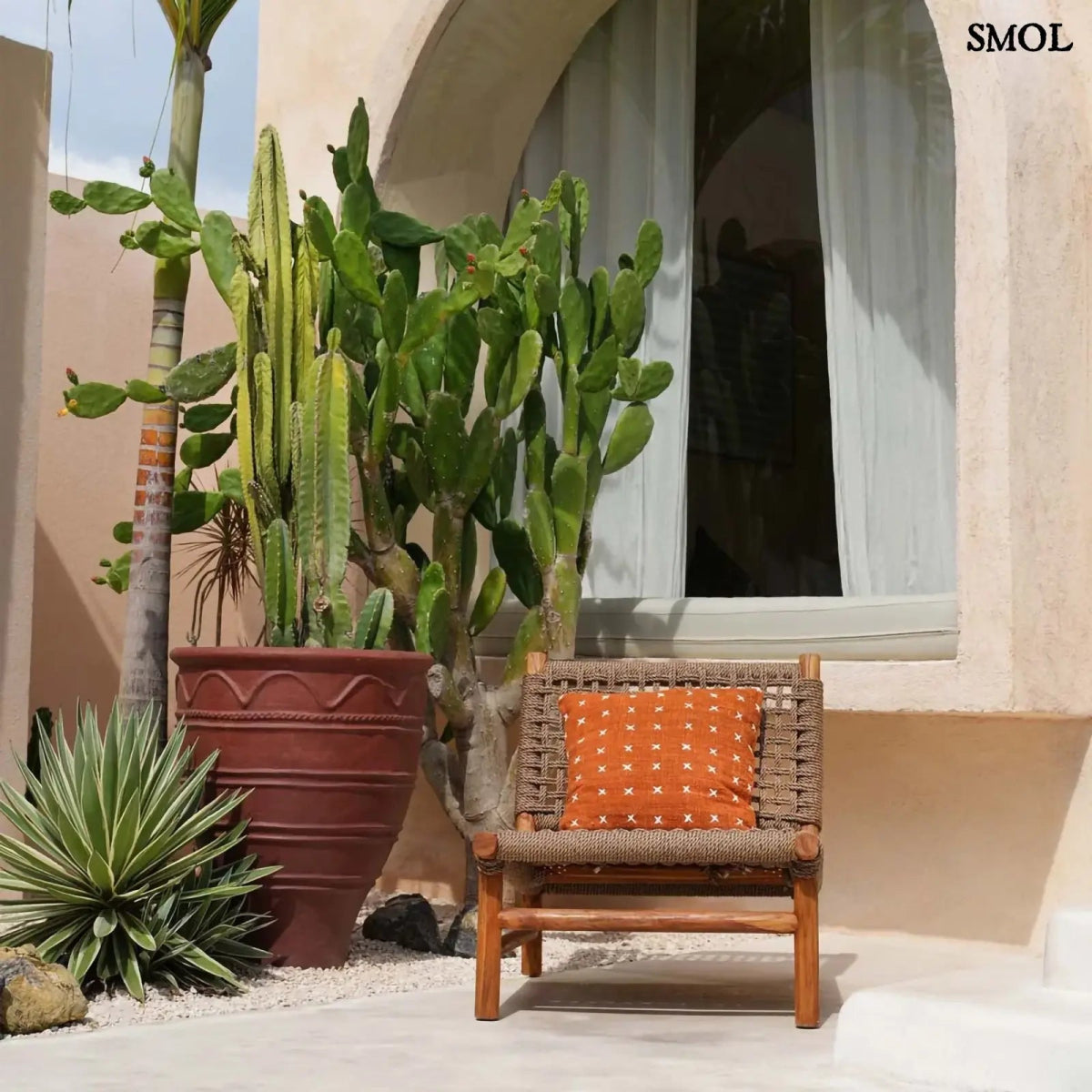 Pamut díszpárnahuzat, élénk terrakotta színben, sűrűn elhelyezett, kézzel varrott fehér kereszt mintákkal, kertben, ablak előtt