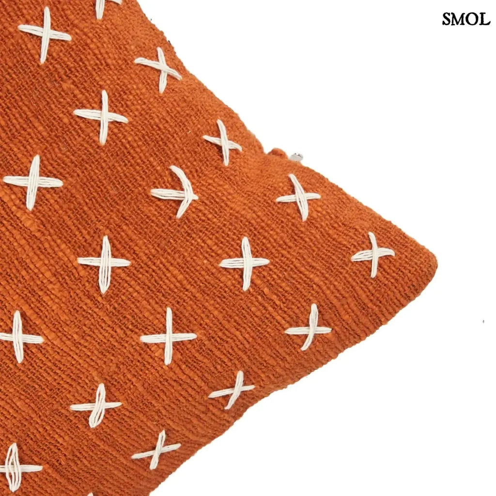 Pamut díszpárnahuzat, élénk terrakotta színben, sűrűn elhelyezett, kézzel varrott fehér kereszt mintákkal, sarok nagyítva