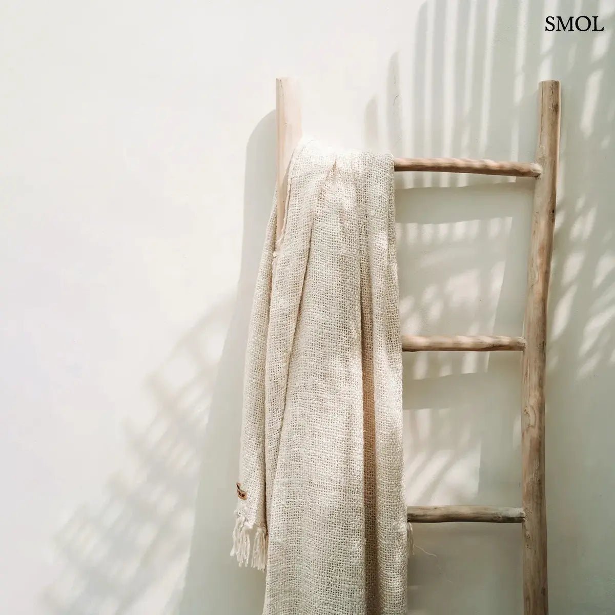 Kézzel szőtt, krémfehér pamut pléd gofri struktúrával és rojtokkal díszítve, létrán