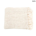 Kézzel szőtt, krémfehér pamut pléd gofri struktúrával és rojtokkal díszítve, fehér háttérrel, összehajtva