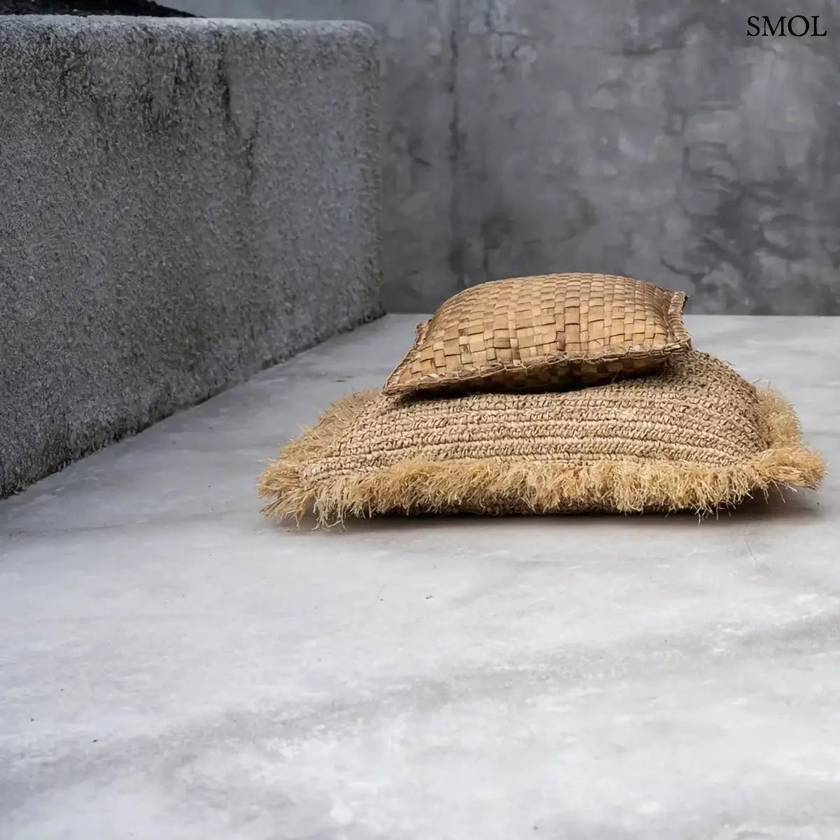 Kézzel szőtt, natúr raffia díszpárnahuzat rojtos szélekkel, 60x60 cm-es méretben, teraszon fektetve