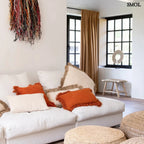 Natúr színű, kézzel font raffia puff kör alakú formával - nappaliban, narancs párnákkal