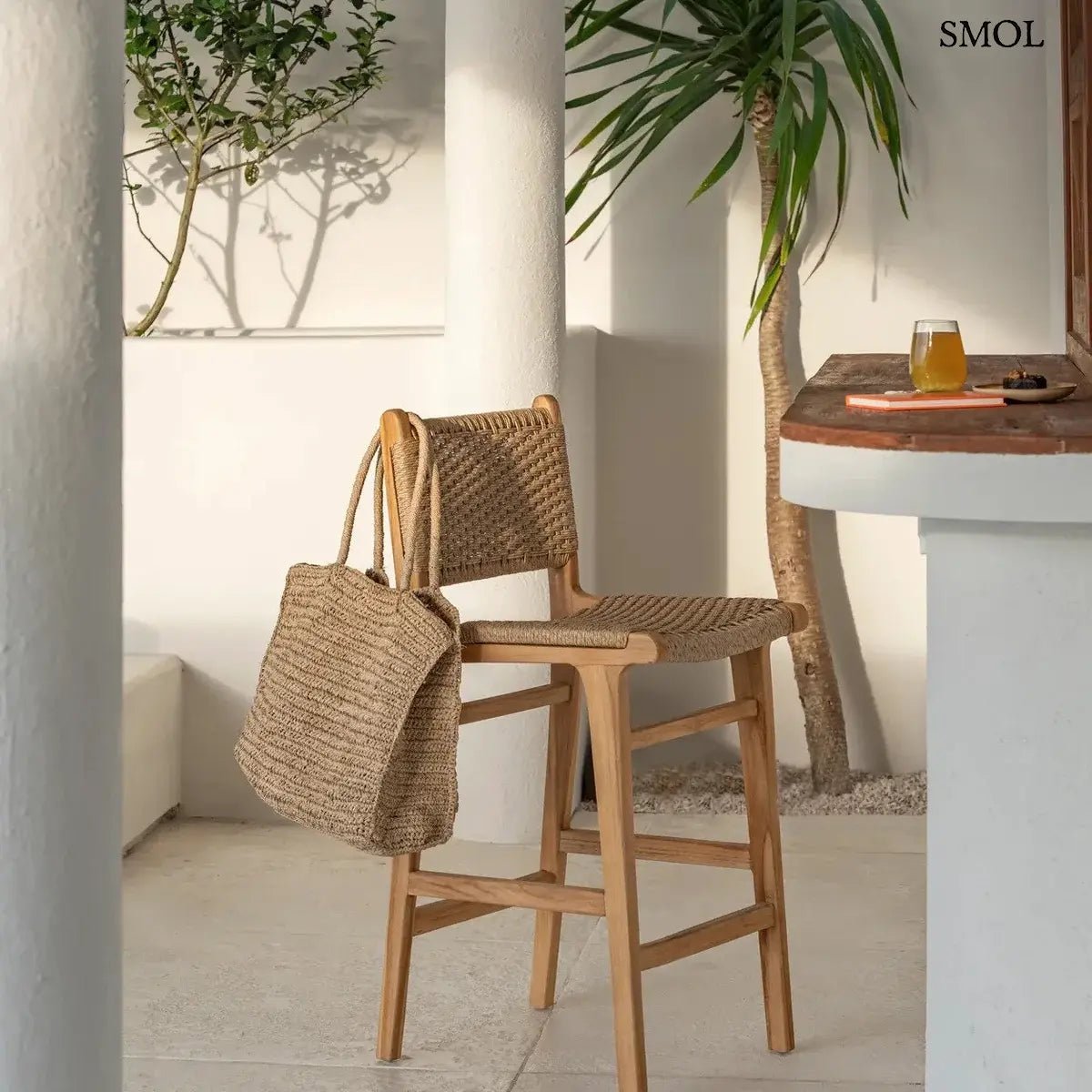 Természetes színű, fonott raffia strandtáska és shopper hosszú vállpántokkal, bárszékre akasztva