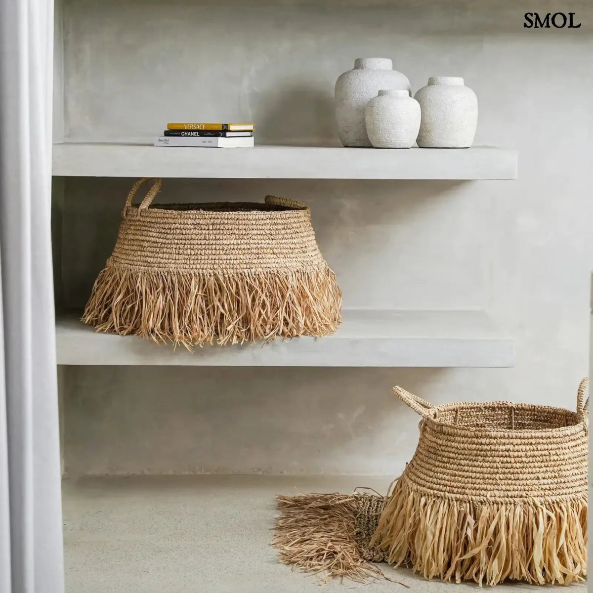 Raffia tárolókosár natúr színben, rojtos boho díszítéssel, fürdőszobában, két méretben