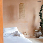 Kézzel szőtt, natúr színű, hosszúkás rattan függőlámpaernyő, alján lelógó, organikus szálakkal, hálószobában