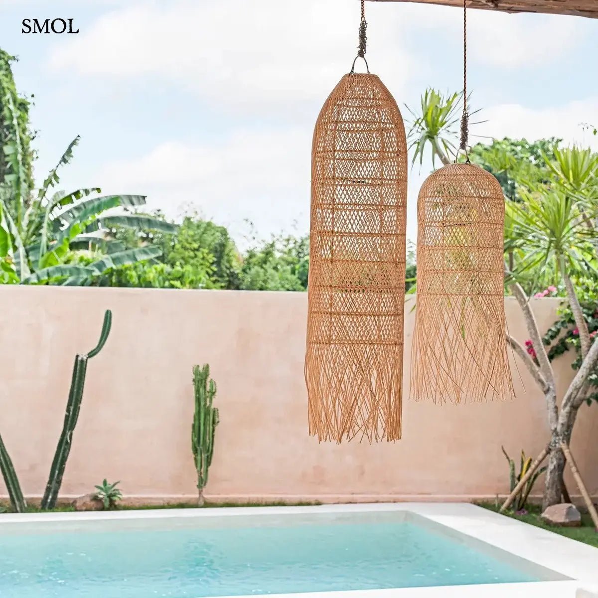 Kézzel szőtt, natúr színű, hosszúkás rattan függőlámpaernyő, alján lelógó, organikus szálakkal, teraszon