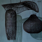 Hosszúkás, fekete színű, kézzel szőtt rattan lámpaernyő, amelynek alján a szálak szabadon, ritmikus vonalakkal végződnek, több fekete lámpaernyővel