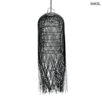 Hosszúkás, fekete színű, kézzel szőtt rattan lámpaernyő, amelynek alján a szálak szabadon, ritmikus vonalakkal végződnek, fehér háttérrel