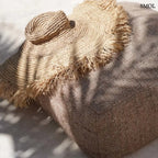 Kézzel szőtt, natúr barna szalmakalap széles, rojtos karimával, barna puffon