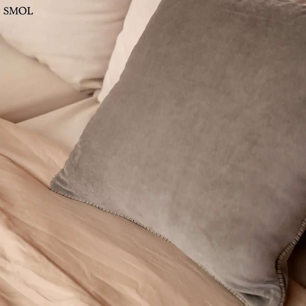 Szürke bársony díszpárnahuzat 50x50 cm méretben, elegáns fonott szegéllyel, ágyon