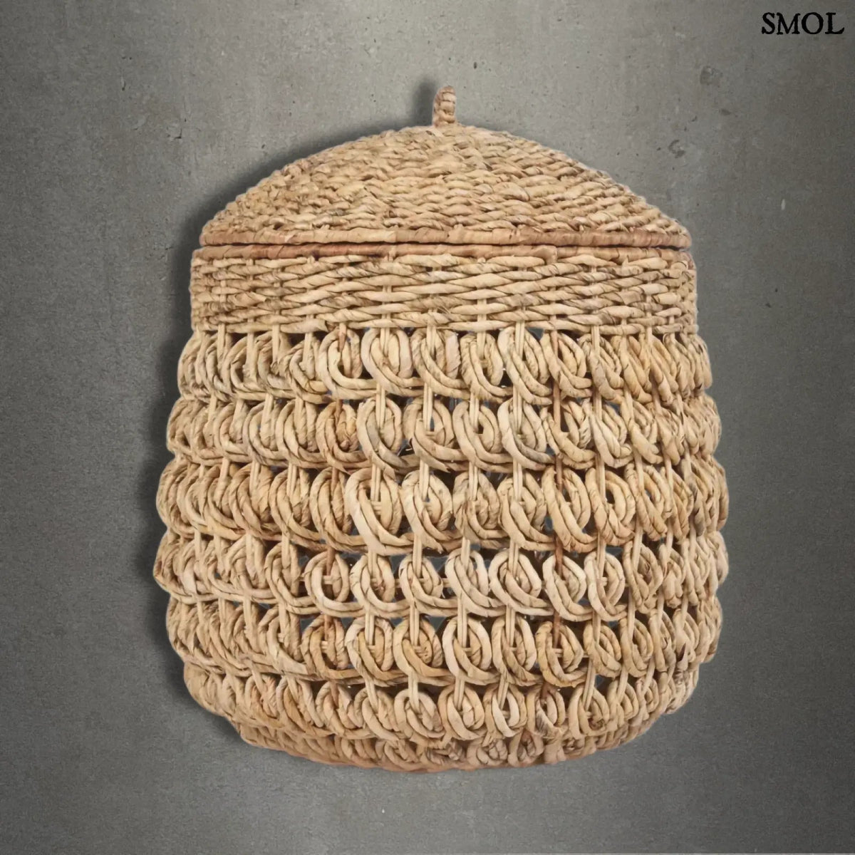 Kézzel fonott banánlevél tároló kosár fedővel, természetes natúr színben. Magas, kerek, szürke háttérrel
