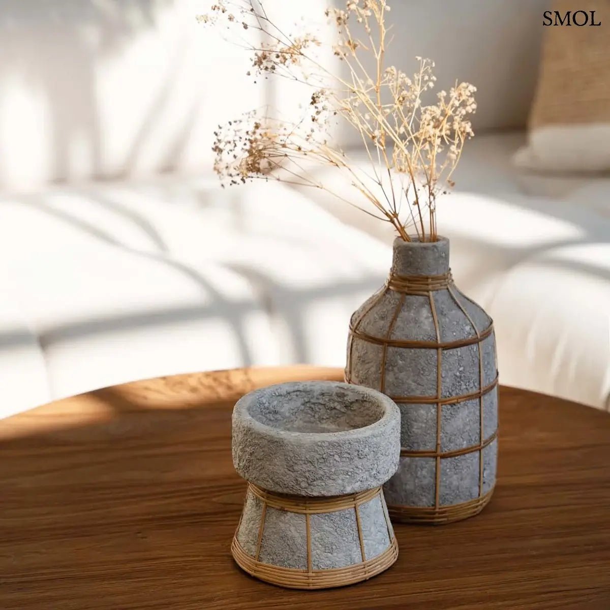 Beton hatású dekor váza kézzel szőtt rattan díszítéssel és rusztikus terracotta felülettel, lerakóasztalon gyertyatartóval