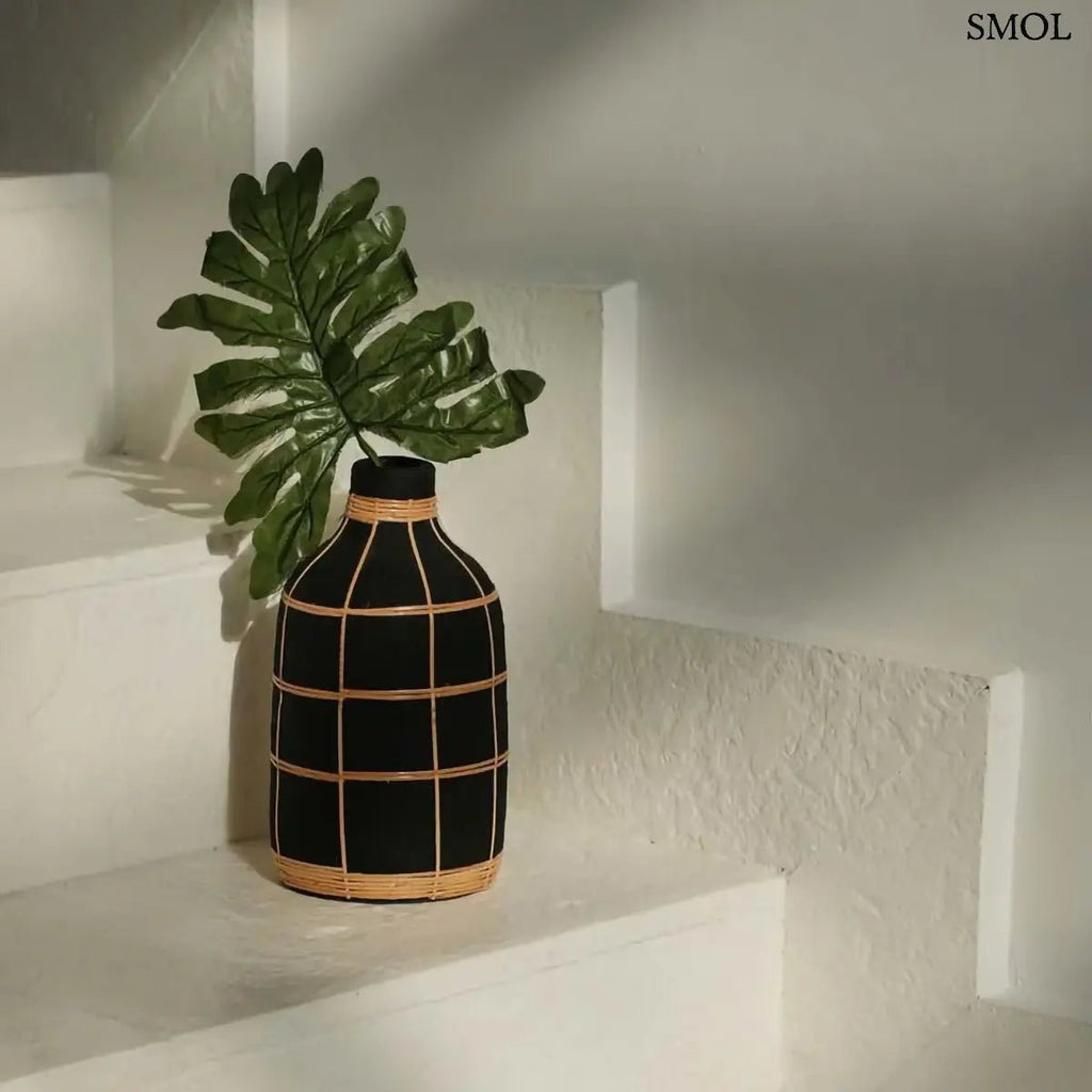 Fekete terracotta váza világos rattan fonattal, rusztikus textúrával, szárazvirágokhoz, lépcsőn, levéllel