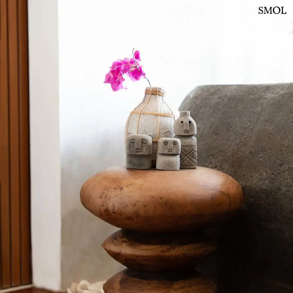 Natúr beton hatású terrakotta váza világos rattan fonattal díszítve, szárazvirágokhoz, lerakóasztalon, szobrokkal