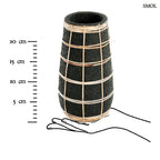 Fekete színű, rusztikus felületű terrakotta váza, amelyet világosbarna, kézzel font rattan rácsozat díszít, méretarányosan