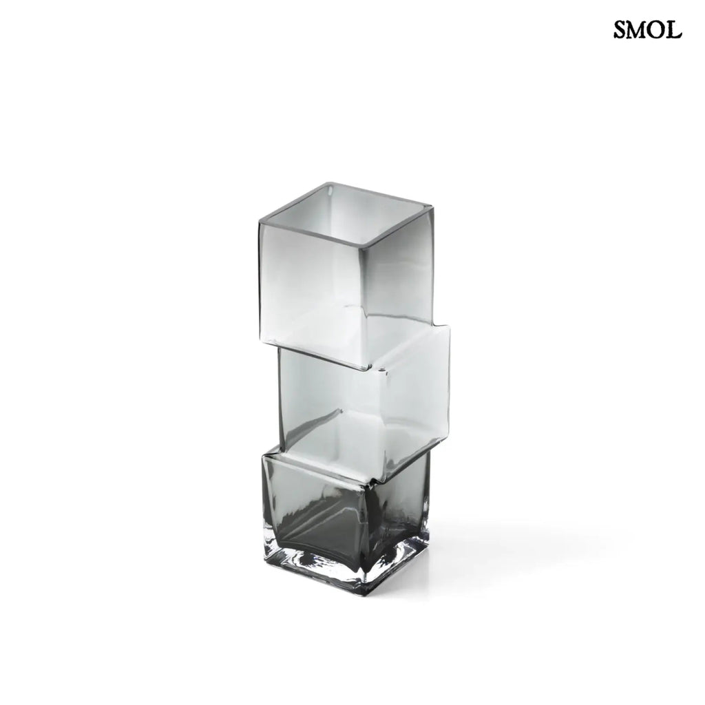 Függőlegesen elrendezett, három kocka alakú sötétszürke üveg váza, fehér háttérrel