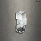 Függőlegesen elrendezett, három kocka alakú sötétszürke üveg váza, szürke háttérrel