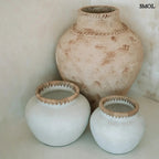 Rusztikus natúr terrakotta váza kézzel font raffia díszítéssel a peremén, kaspóval, sarokban